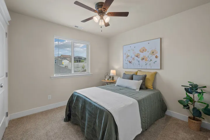 Carpeted bedroom featuring a ceiling fan with integrated lighting, a window with horizontal blinds, and a built-in closet with white paneled doors