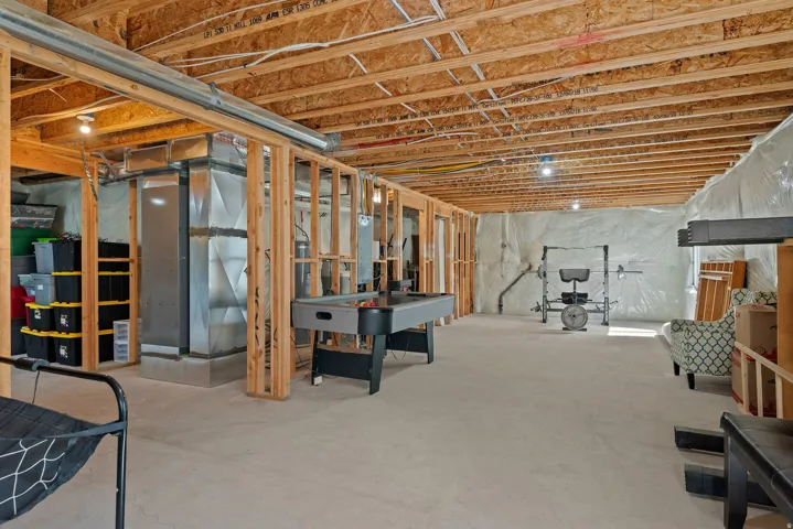 Unfinished basement featuring exposed wood joists and concrete flooring