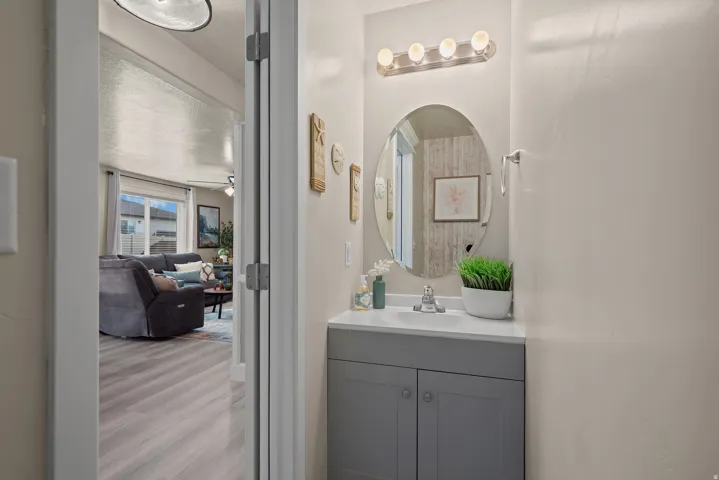 Powder room featuring a gray vanity with a white countertop, an oval mirror, and a five-light vanity fixture
