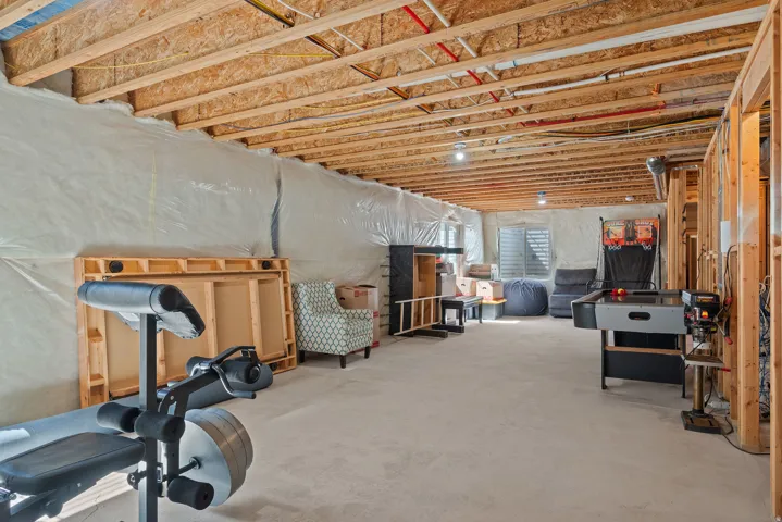 Unfinished basement featuring exposed wood joists, concrete flooring, and framed partitioning