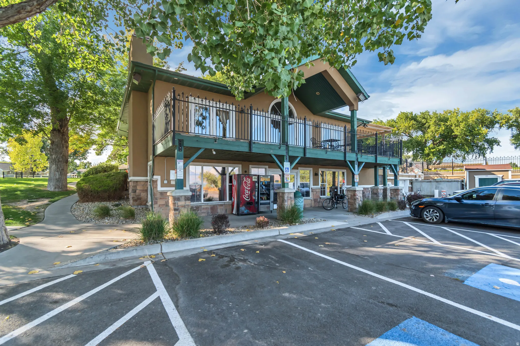 Two-story building featuring a stucco exterior with stone accents, an upper-level balcony with black iron railings, and a ground-level patio area