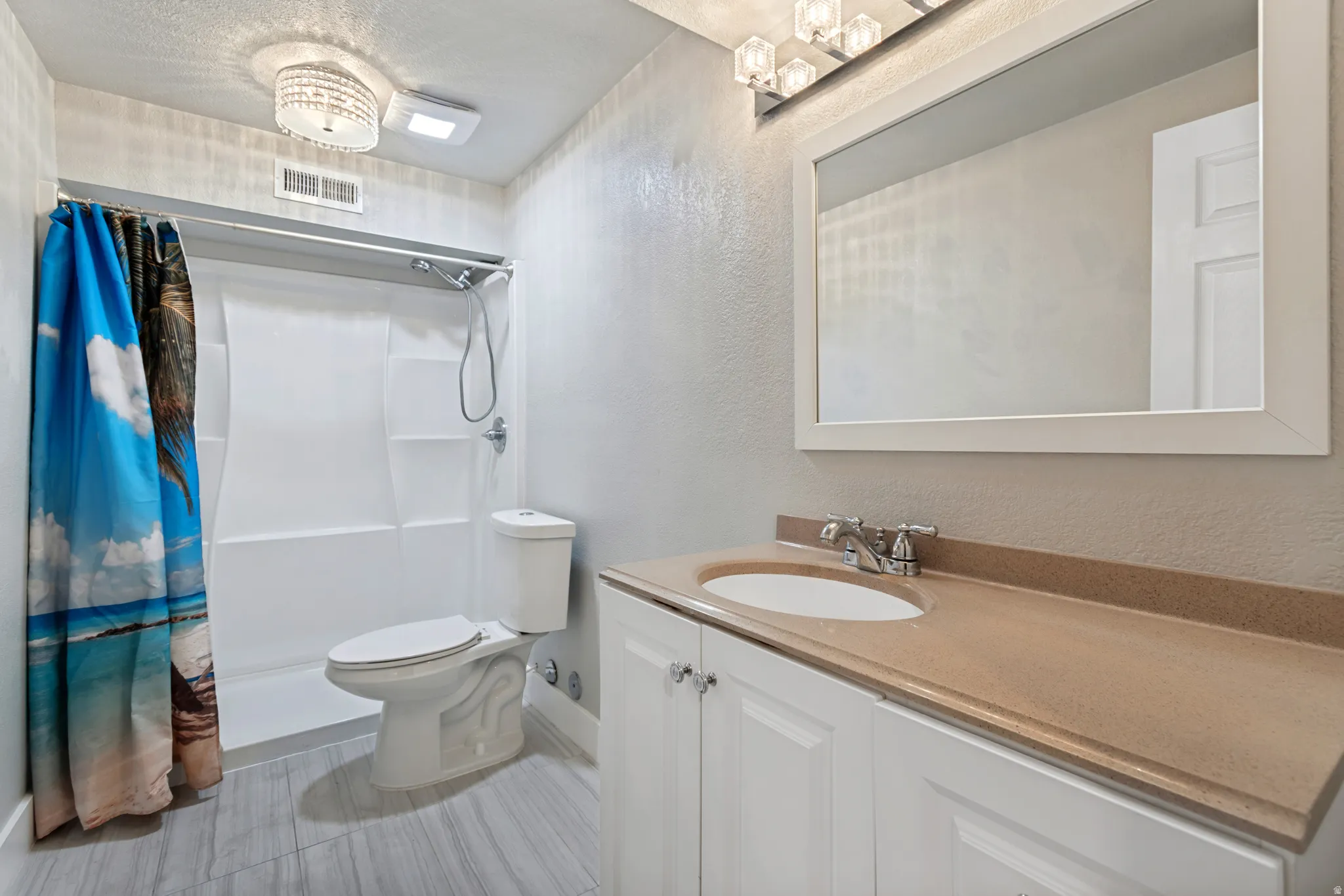 Bathroom featuring a white vanity with a brown countertop, an undermount sink, and a rectangular framed mirror