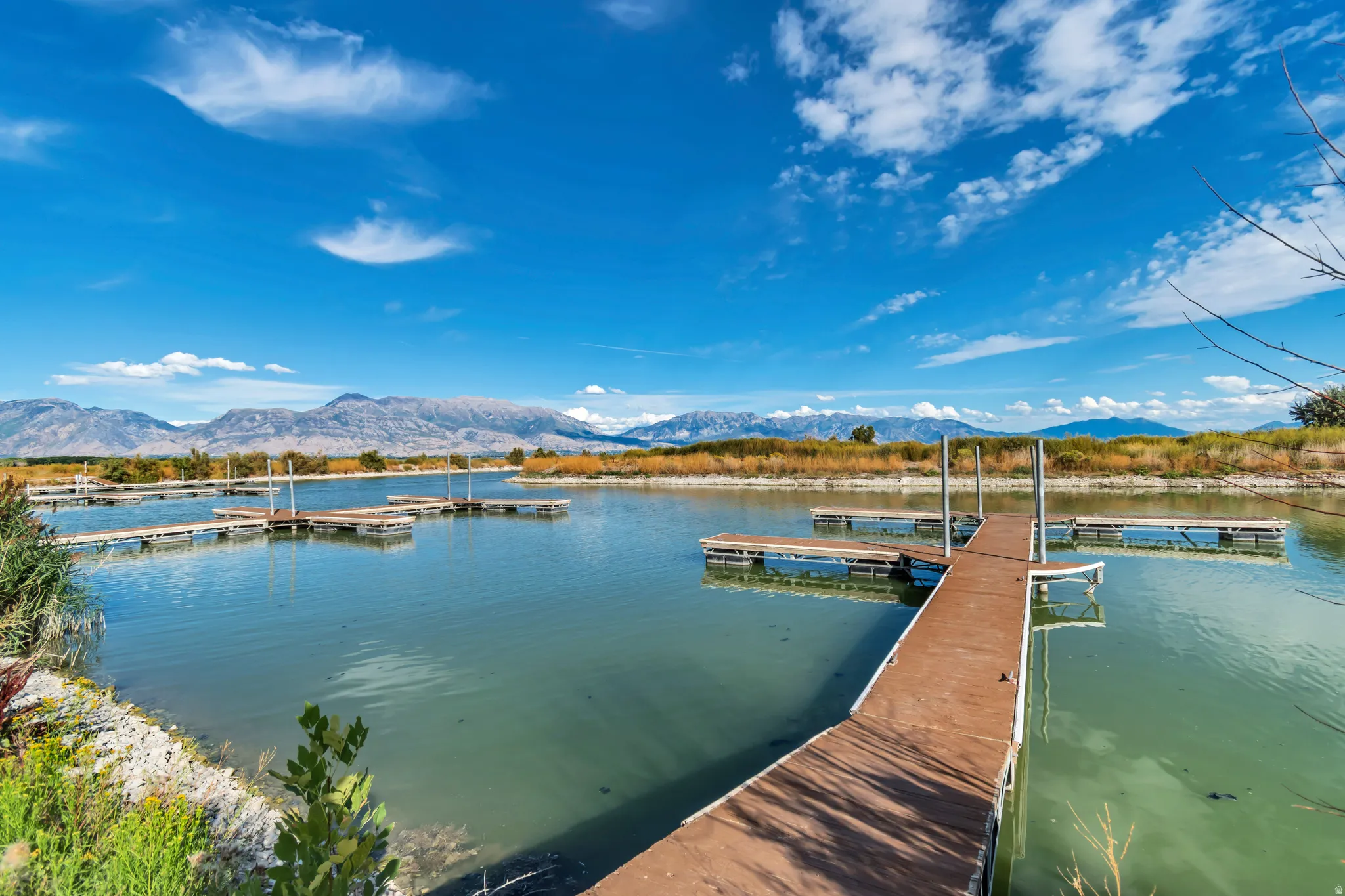 Private boat dock access with multiple slips, featuring a calm waterway, natural shoreline, and distant mountain scenery