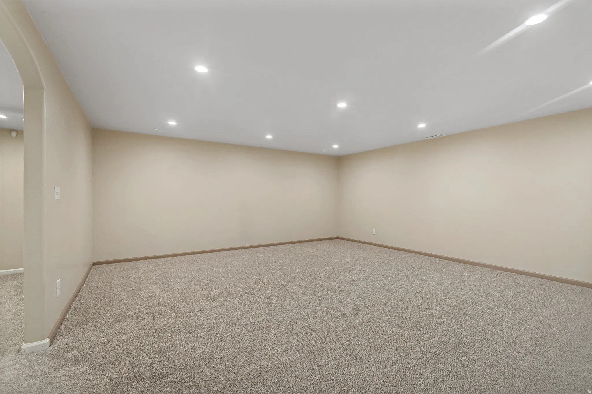 Spacious room featuring neutral carpeting, light-toned walls, and recessed lighting throughout