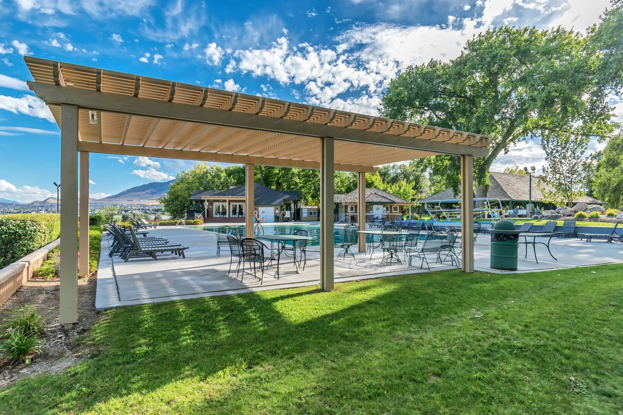 Covered patio area with slatted roof design and concrete flooring