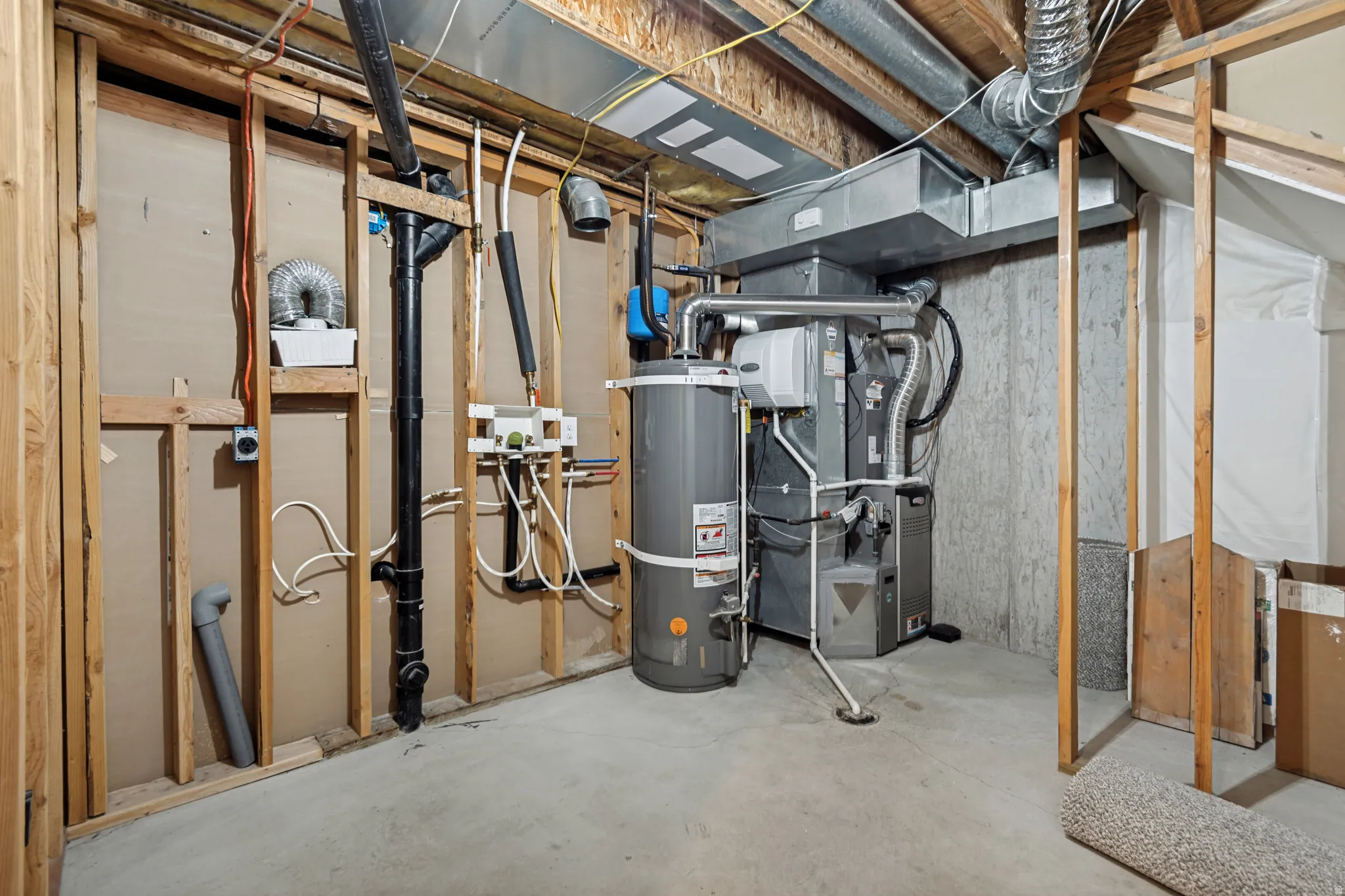 Basement utility area featuring a water heater, furnace, exposed wood framing, concrete flooring, and visible ductwork