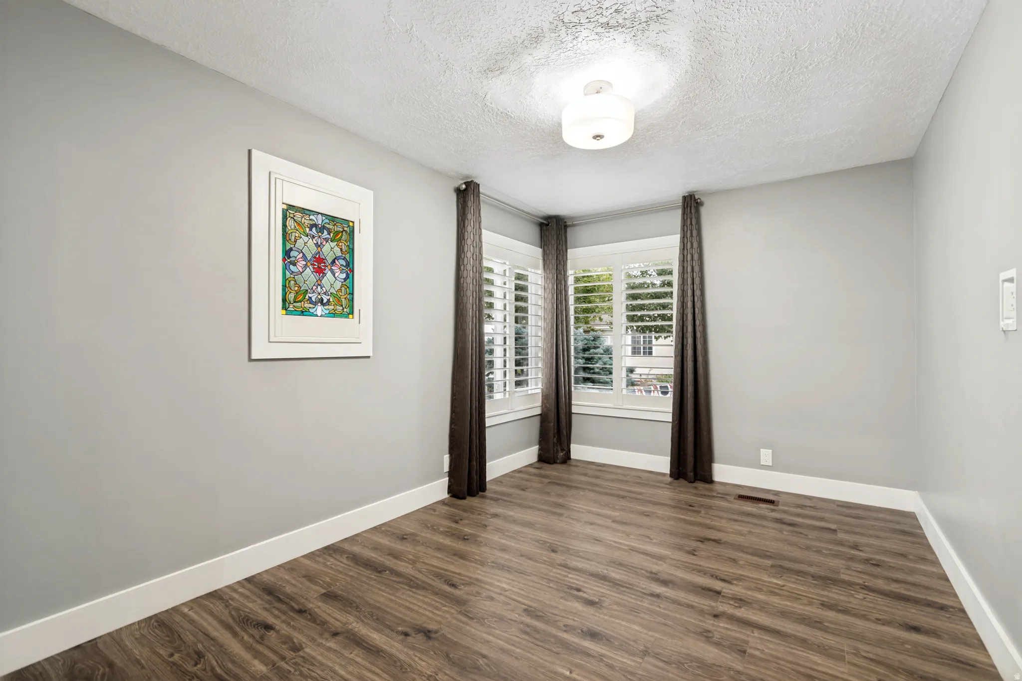 Spacious room featuring wood-finish flooring, light grey walls, and white trim