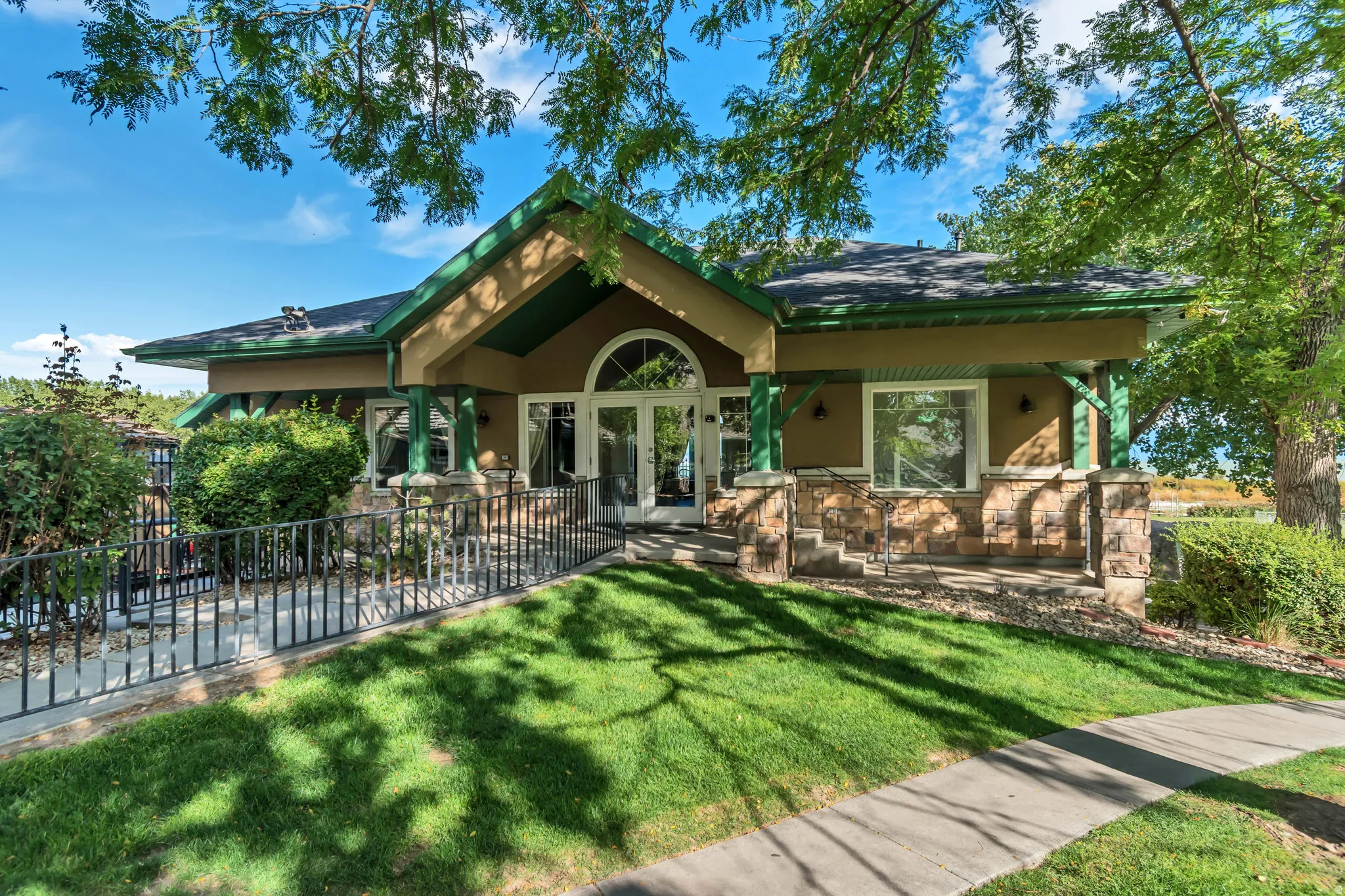 Craftsman-style exterior featuring a prominent arched entry, dual French doors, and stone veneer accents