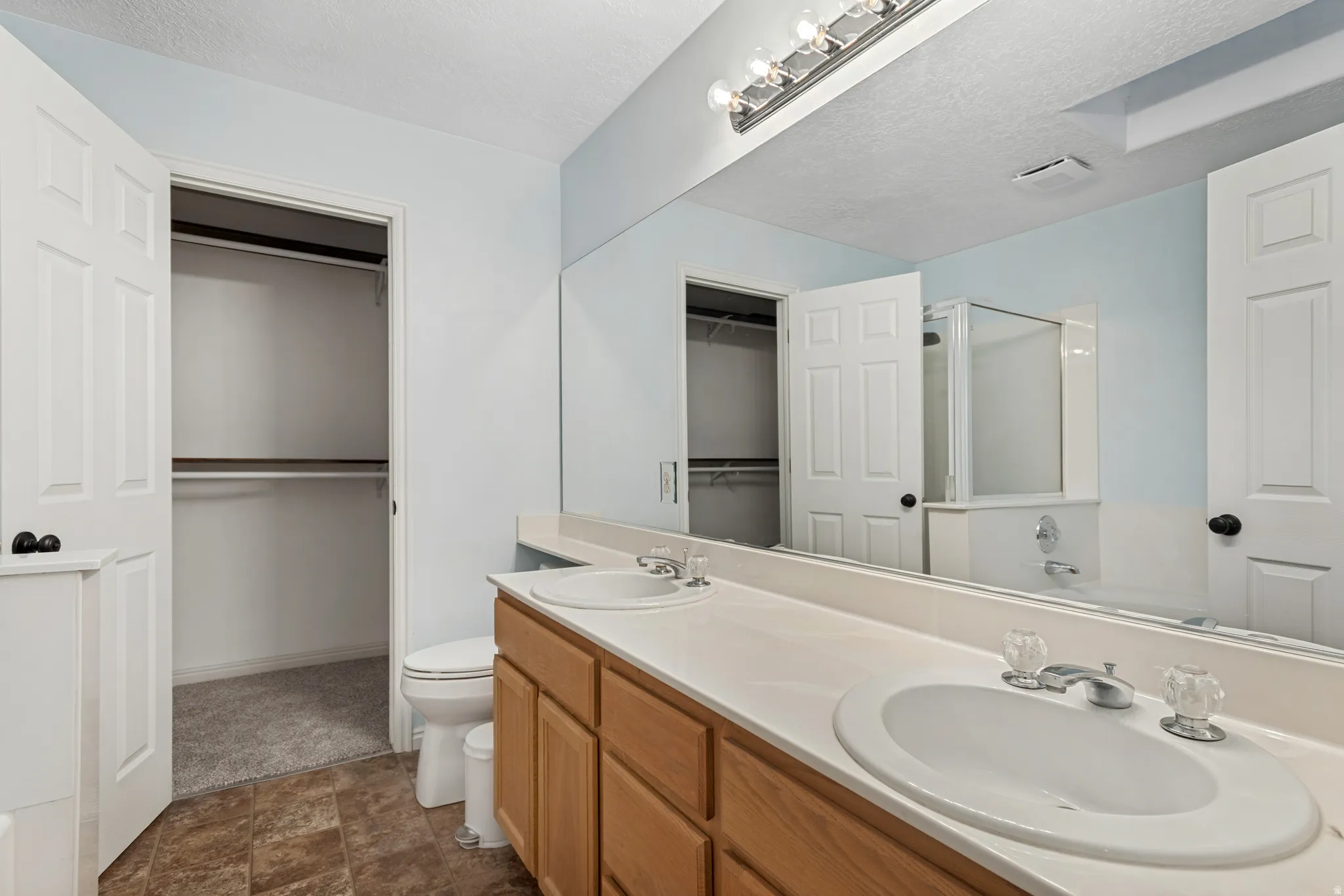 Bathroom featuring a double vanity with wood cabinetry and light-toned countertops