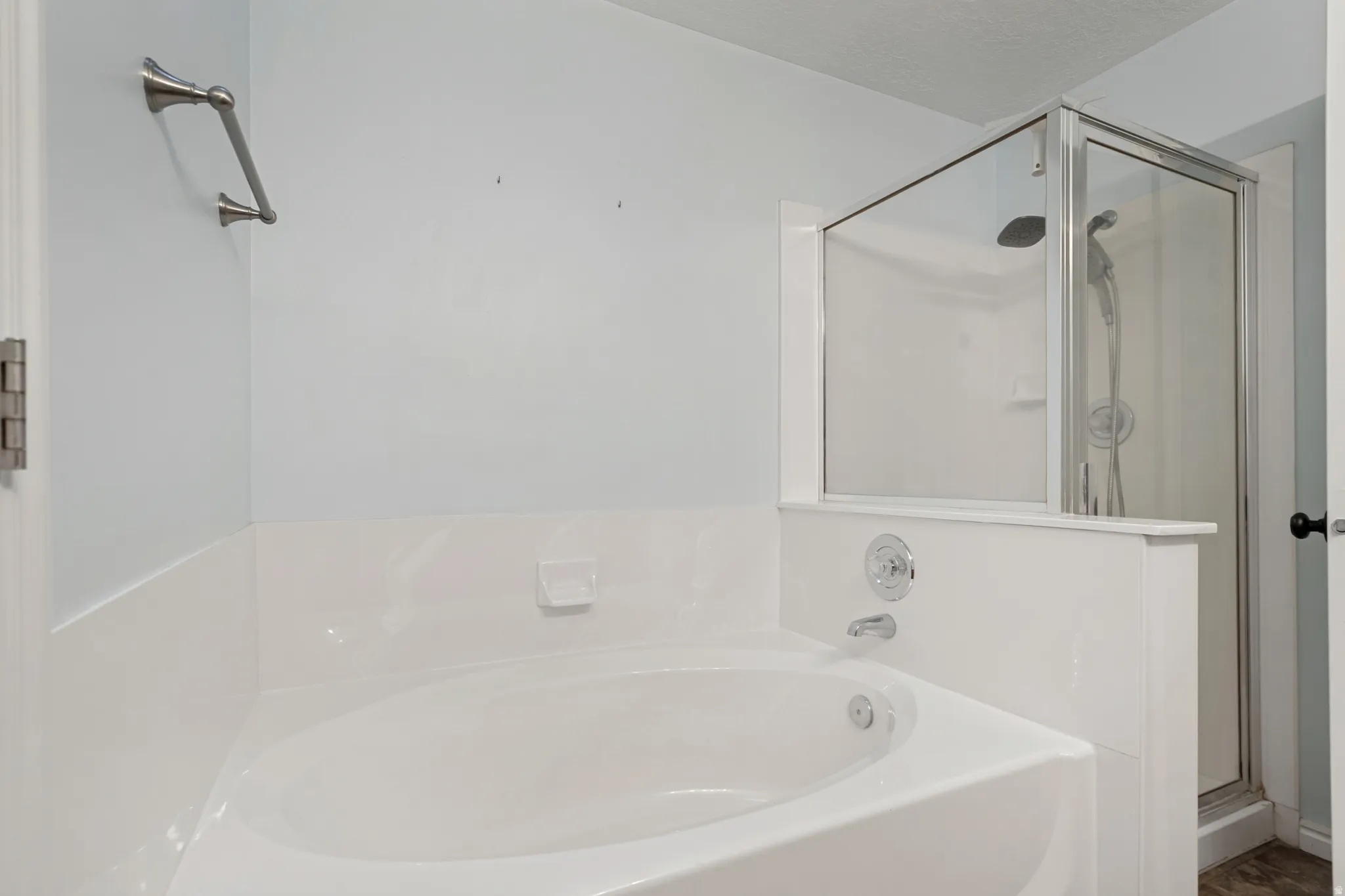 White soaking tub featuring chrome fixtures and a separate glass-enclosed shower