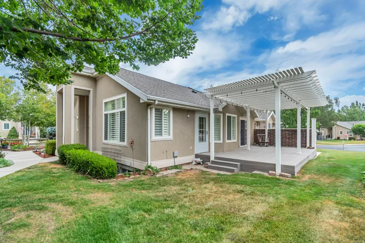 Rear exterior featuring a multi-level composite deck with a white pergola, brick accent wall, and multiple entry points