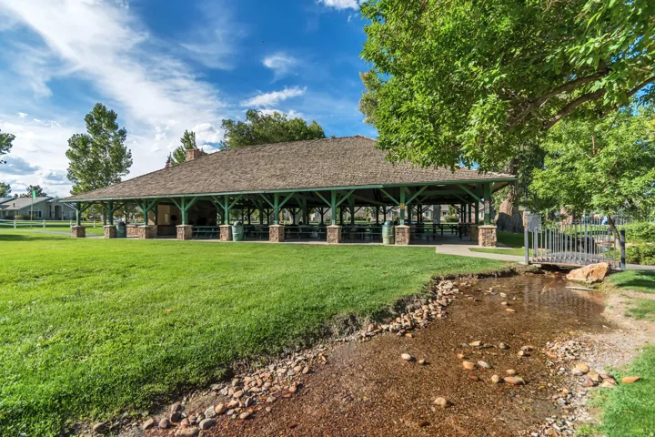 Expansive green space featuring a large pavilion with a brown shingle roof and green beam structure