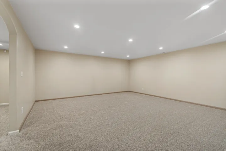 Spacious room featuring neutral carpeting, light-toned walls, and recessed lighting throughout