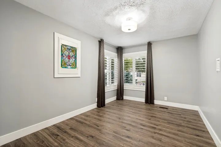 Spacious room featuring wood-finish flooring, light grey walls, and white trim