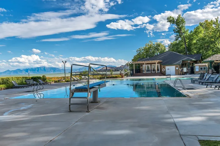 Outdoor swimming pool featuring a diving board, surrounding concrete patio, and lounge chairs