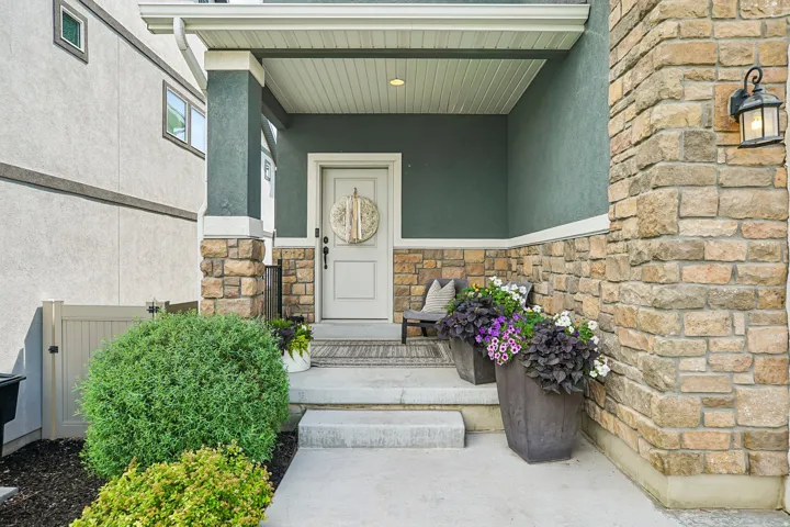 Covered porch entry featuring stone veneer accents and a painted stucco exterior