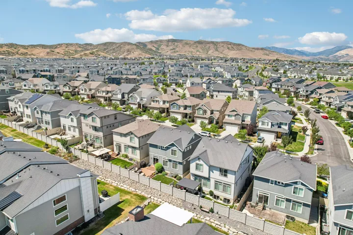 Expansive residential community featuring diverse architectural styles, visible mountain backdrop, paved streets, and numerous single-family homes with private backyards