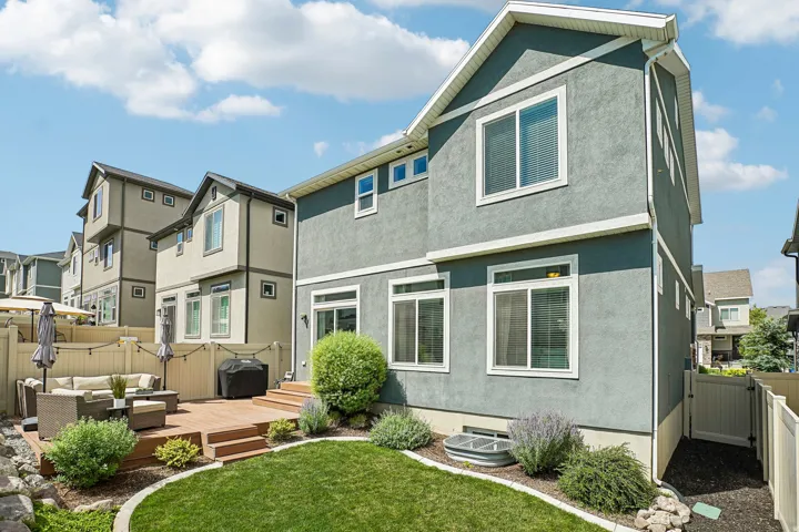 Rear exterior featuring a multi-level wood deck, a manicured lawn, and perimeter landscaping