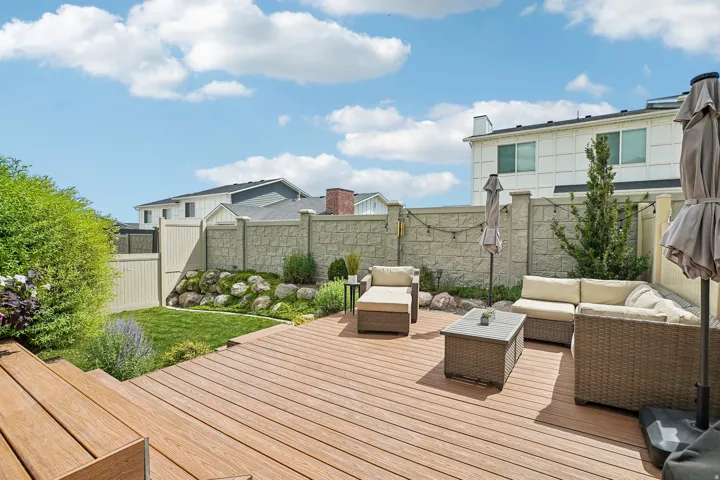 Expansive outdoor decking with a textured finish, bordered by a manicured lawn and garden beds