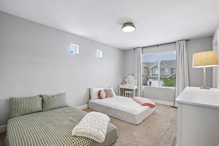 Carpeted room featuring a large window with blinds and curtains, two upper transom windows, and a flush-mount ceiling light fixture