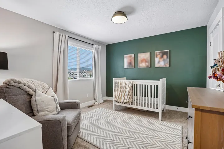 Carpeted room featuring a window with horizontal blinds, a ceiling-mounted light fixture, and a contrasting accent wall