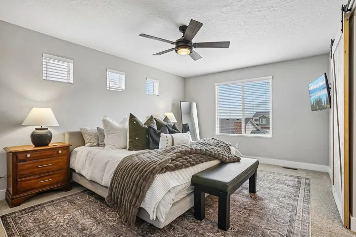 Spacious room featuring multiple windows, a ceiling fan with integrated lighting, and a barn door