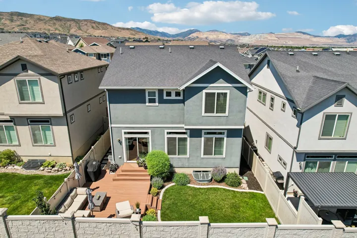 Rear exterior featuring a multi-level wood-finish deck, sliding glass door access, and a manicured lawn