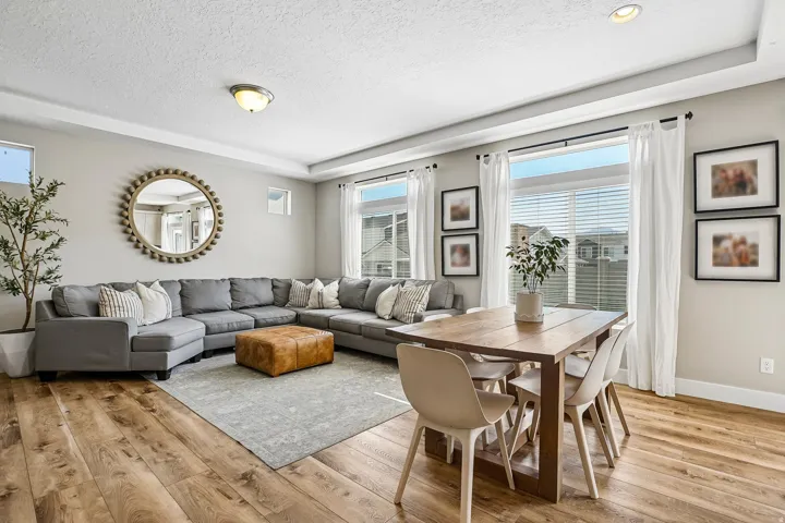Open concept living and dining area featuring wood-finish flooring, recessed lighting, and large windows with blinds