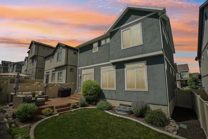 Private backyard featuring a terraced wood-finish deck with integrated steps, a manicured lawn area, and established shrubbery