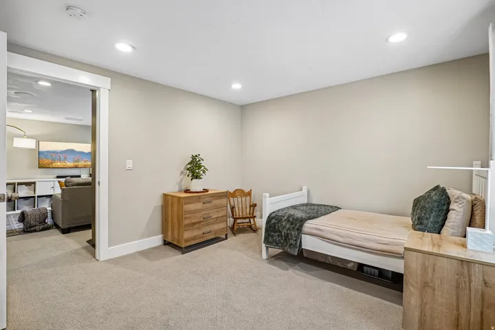 Carpeted room with recessed lighting, an open doorway leading to a separate living area, and neutral wall tones