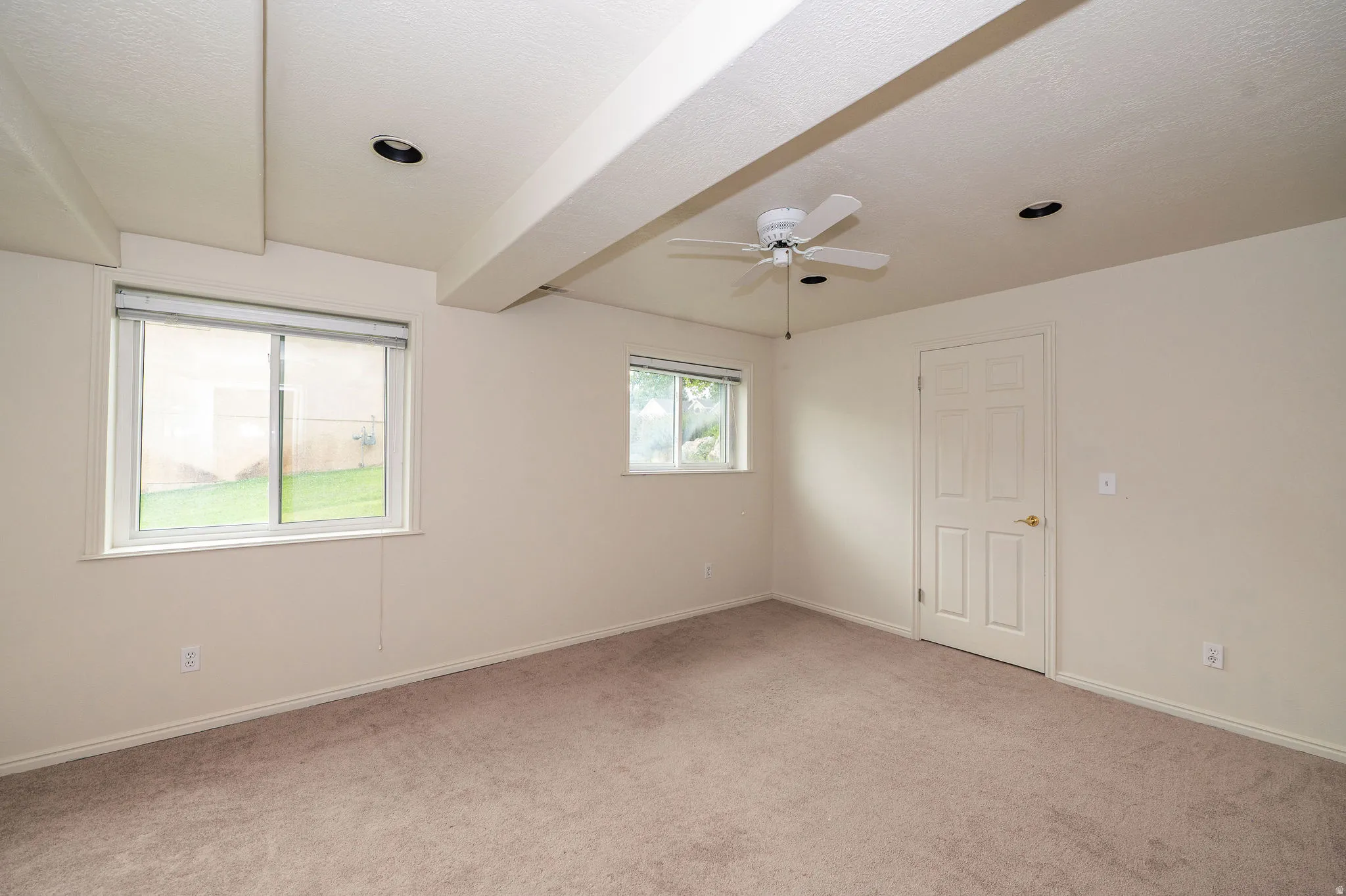 Carpeted room featuring two windows, a white ceiling fan, and recessed lighting