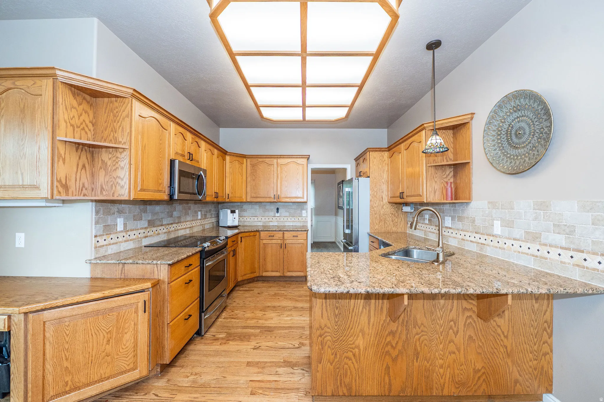 Kitchen featuring wood-finish cabinetry, granite countertops, stainless steel appliances, and a tiled backsplash