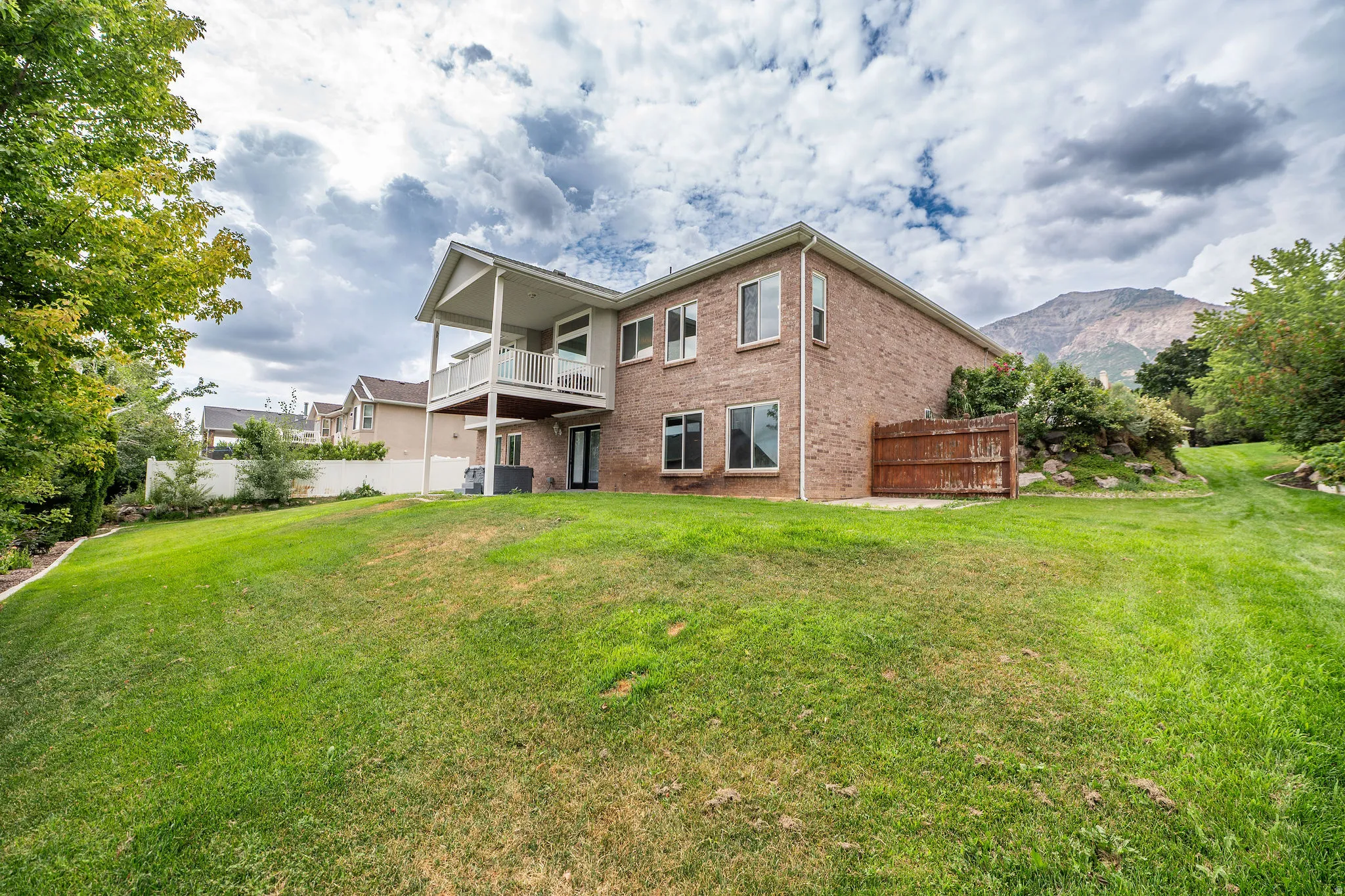 Spacious backyard featuring an elevated covered balcony and mountain backdrop