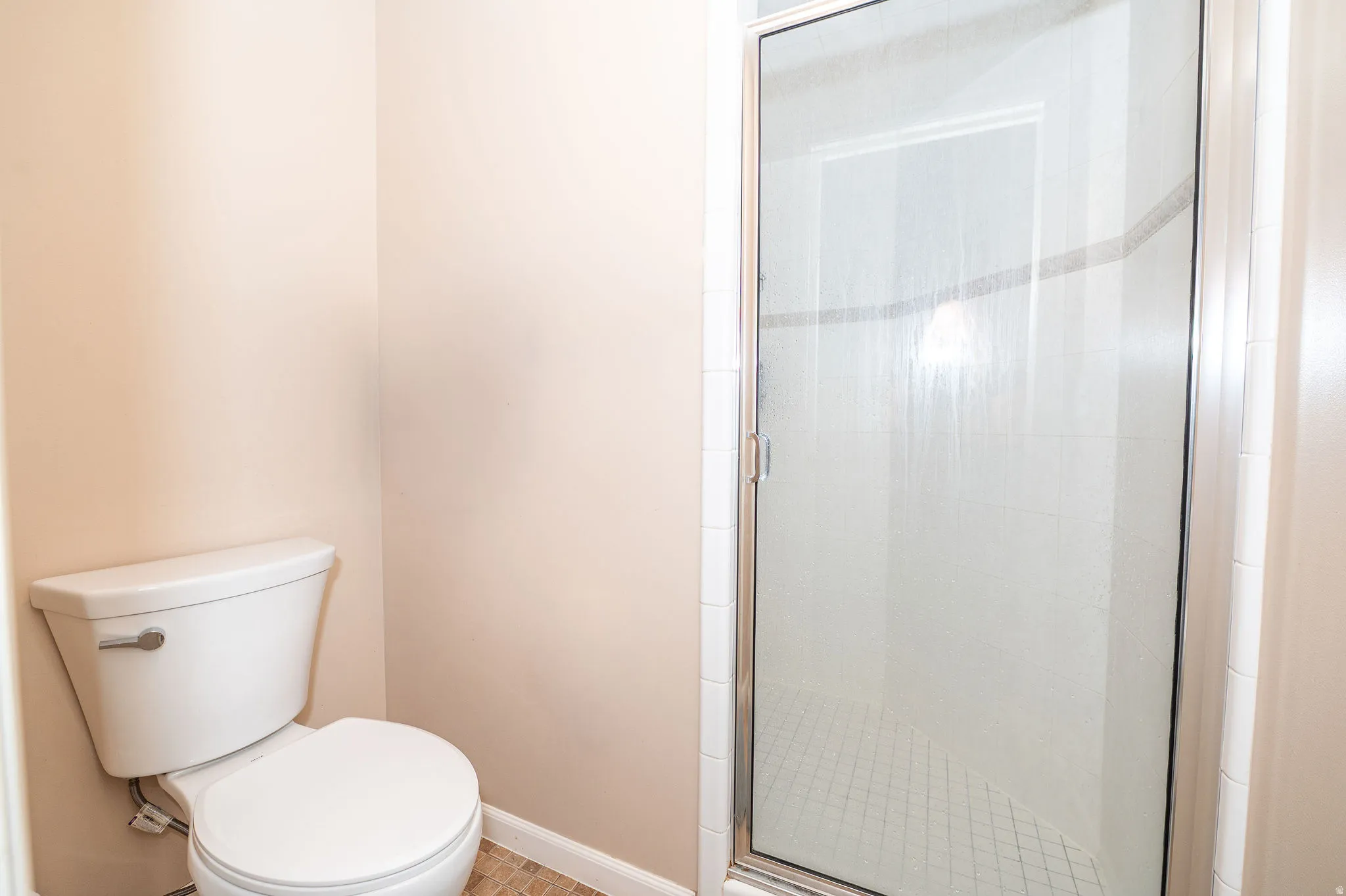 Walk-in shower with clear glass enclosure and white tile surround