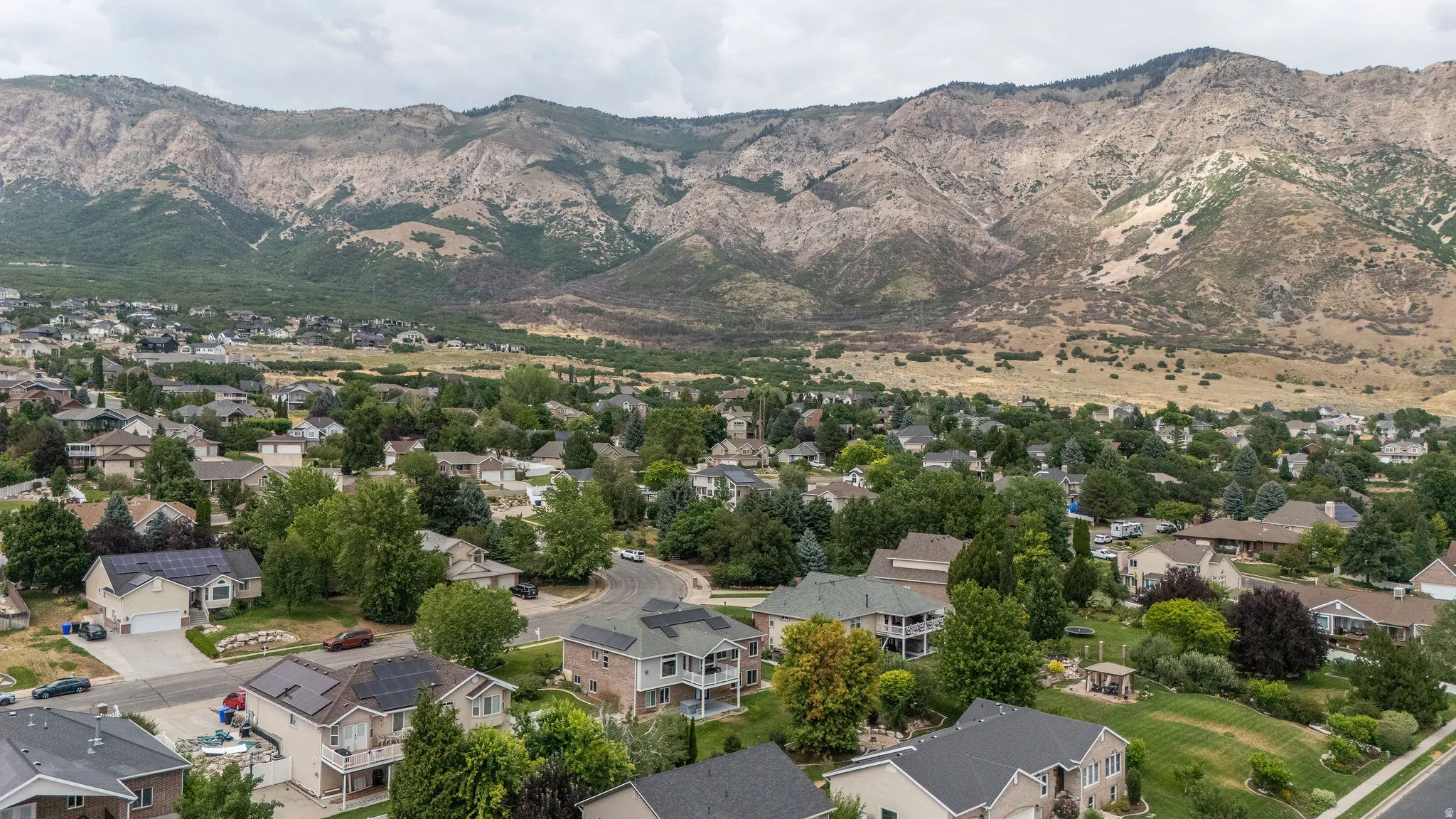Residential neighborhood featuring diverse architectural styles and mature landscaping against a mountain backdrop