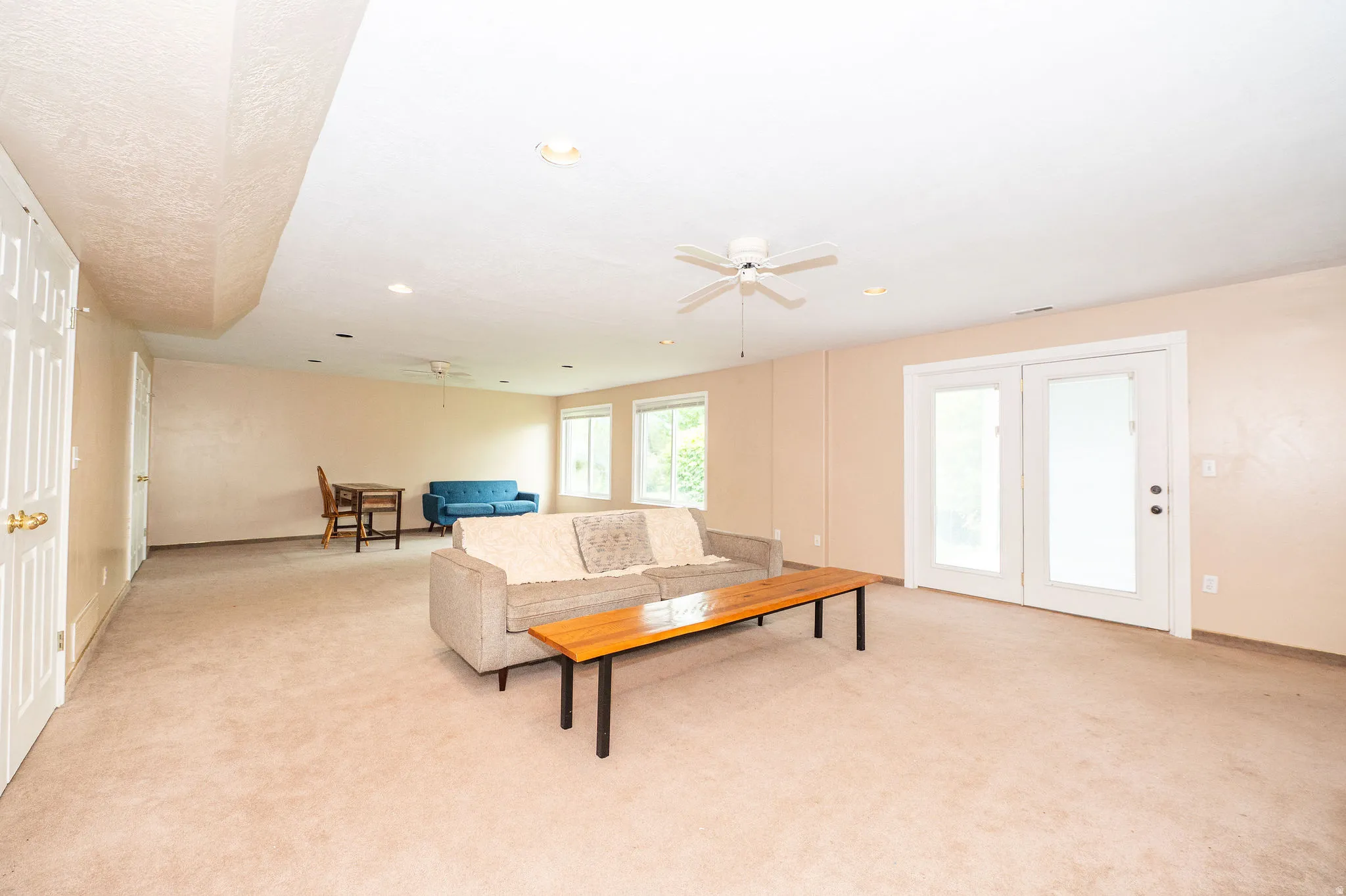 Spacious room featuring carpet flooring, recessed lighting, a ceiling fan, and double patio doors with frosted glass