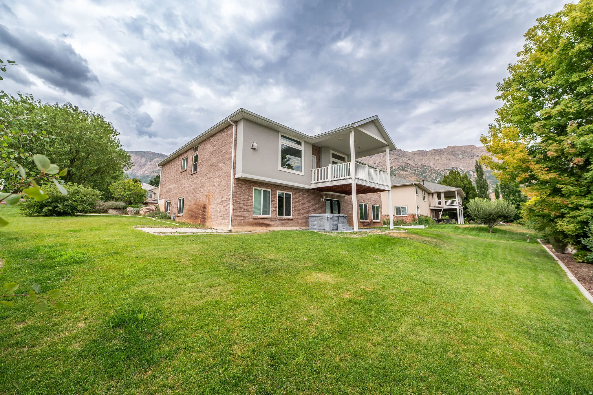 Expansive backyard featuring a manicured lawn, established landscaping, and mature trees