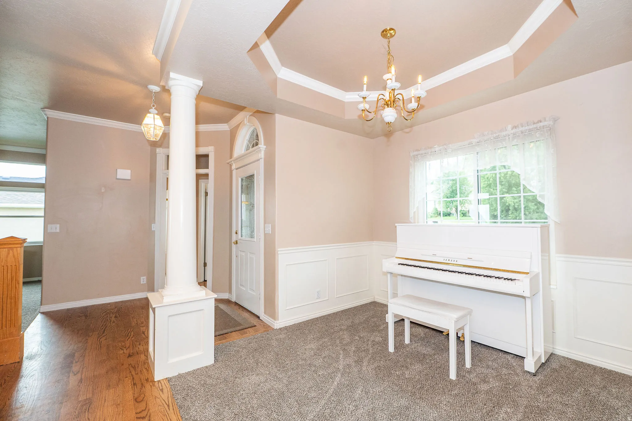 Entryway featuring a decorative column, an arched transom window above the front door, and a tray ceiling