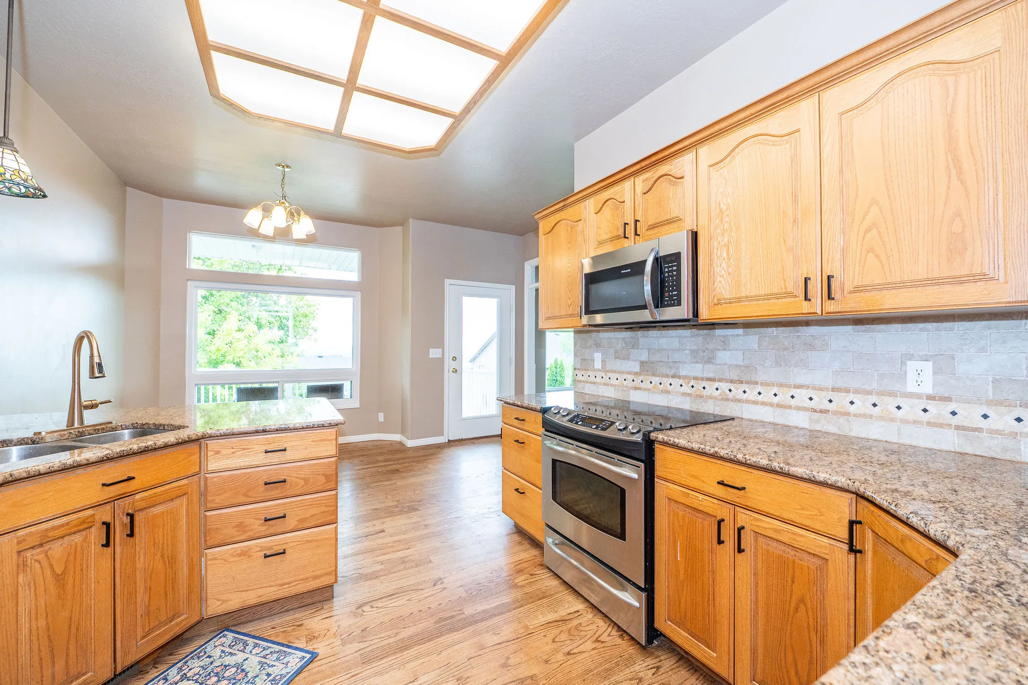 Kitchen featuring wood-finish cabinetry, granite-style countertops, stainless steel appliances, a tiled backsplash, and recessed lighting
