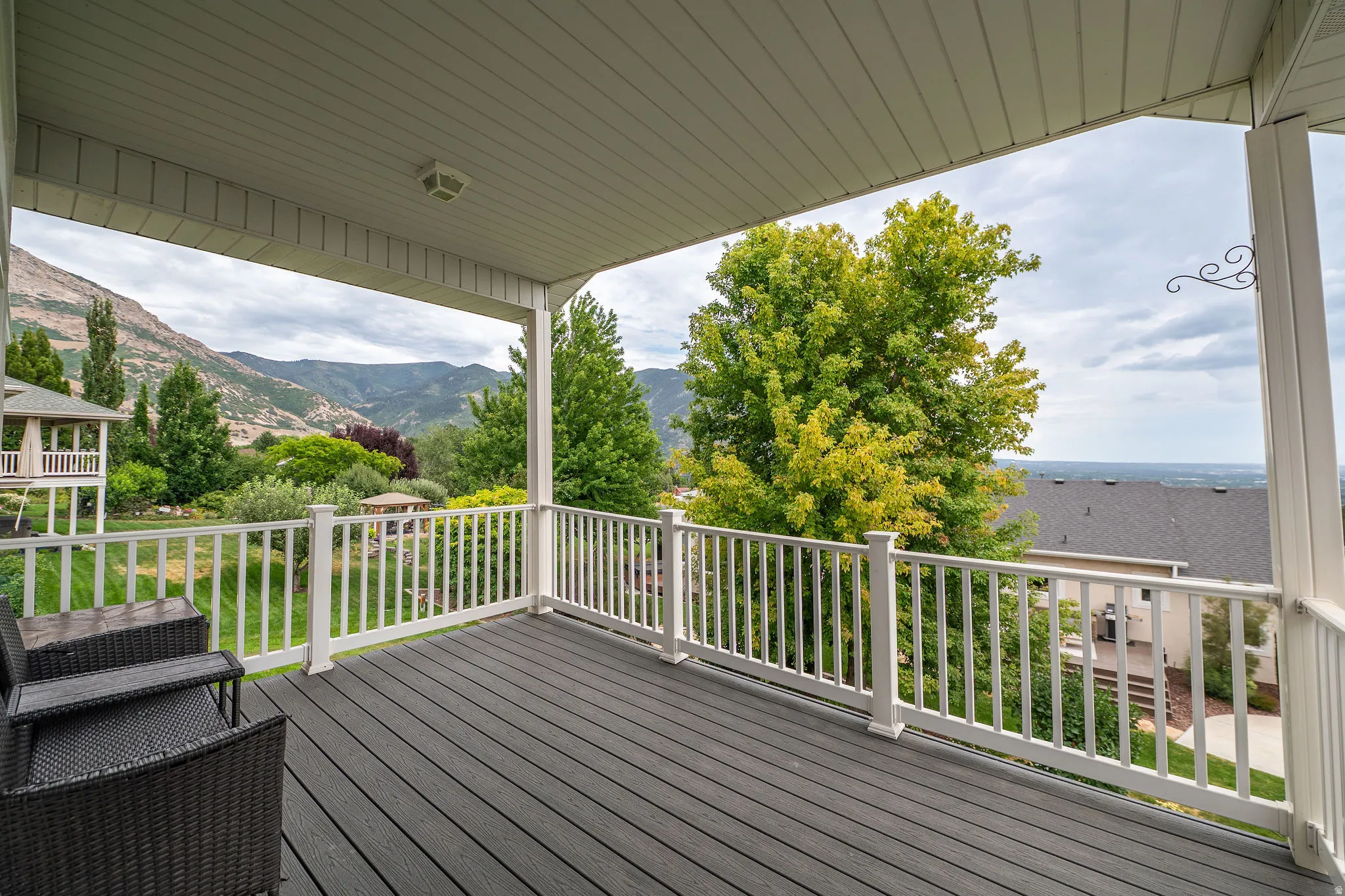 Expansive covered balcony featuring dark composite decking, white balusters, and a white ceiling with recessed lighting