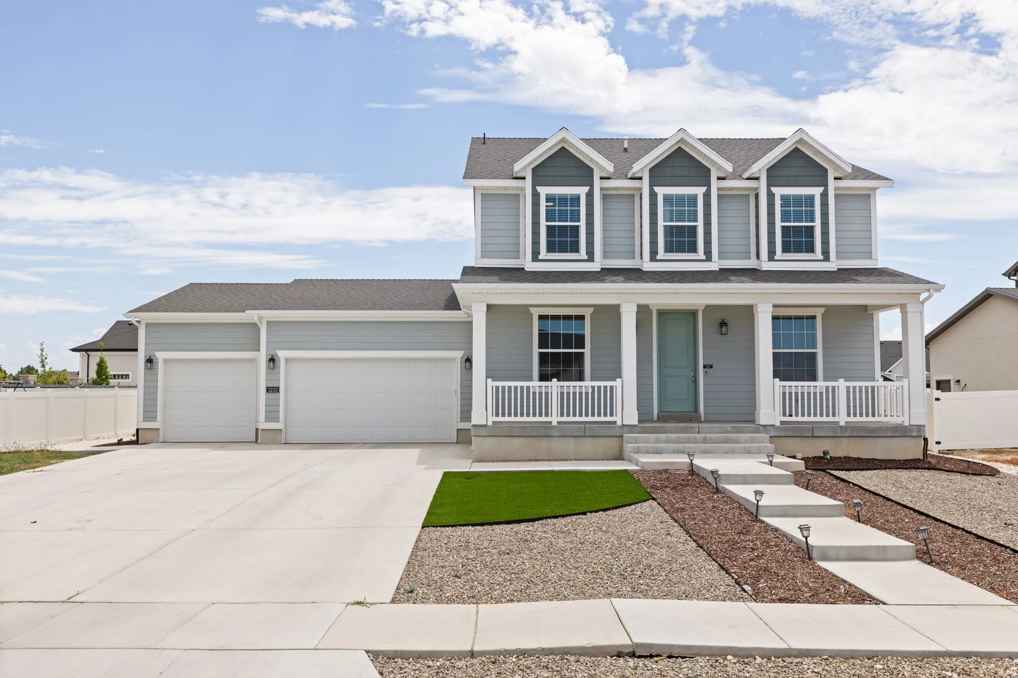 Two-story residence featuring light gray siding with dark gray shingle accents and a covered front porch with white railings