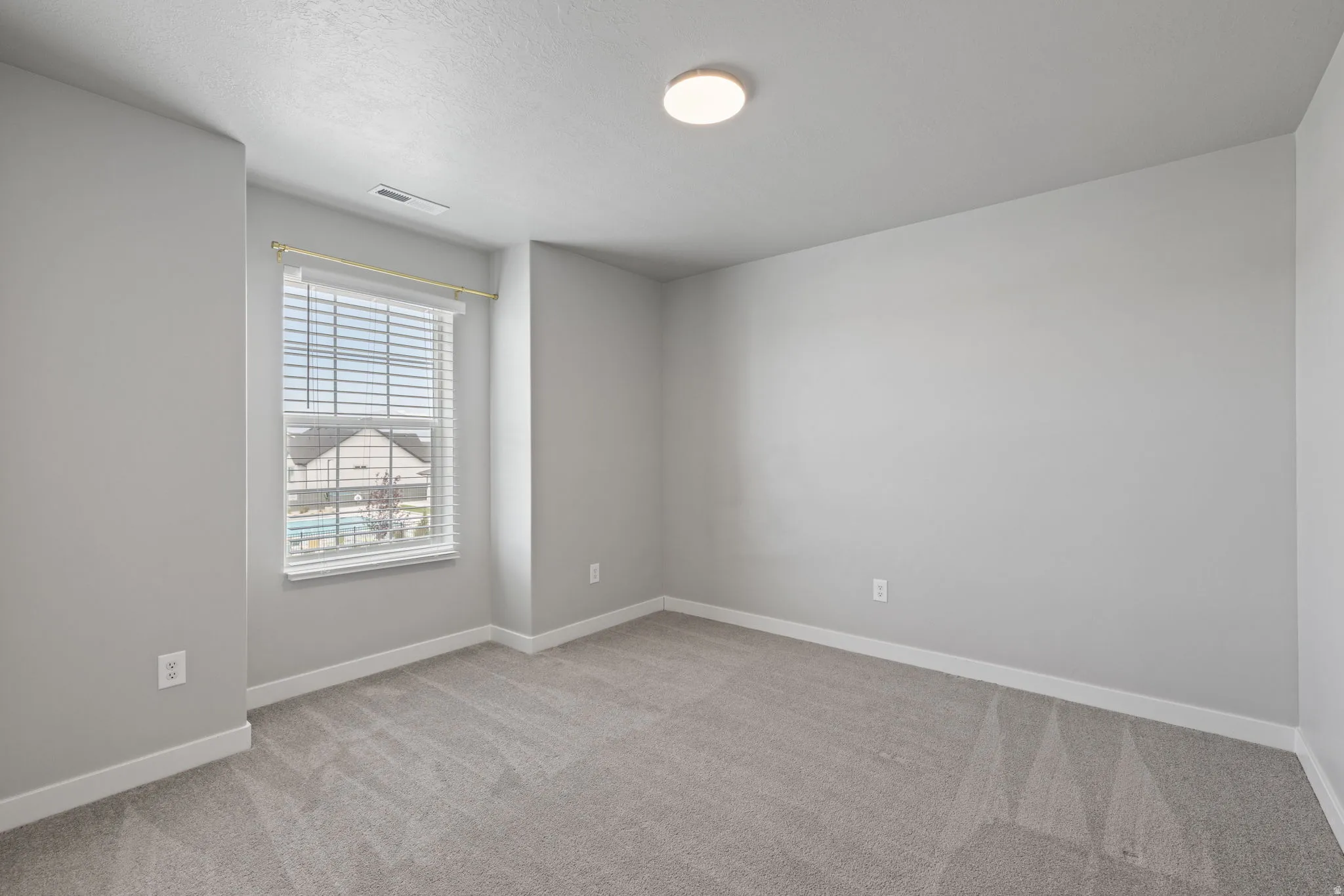 Carpeted room with a double-hung window featuring horizontal blinds