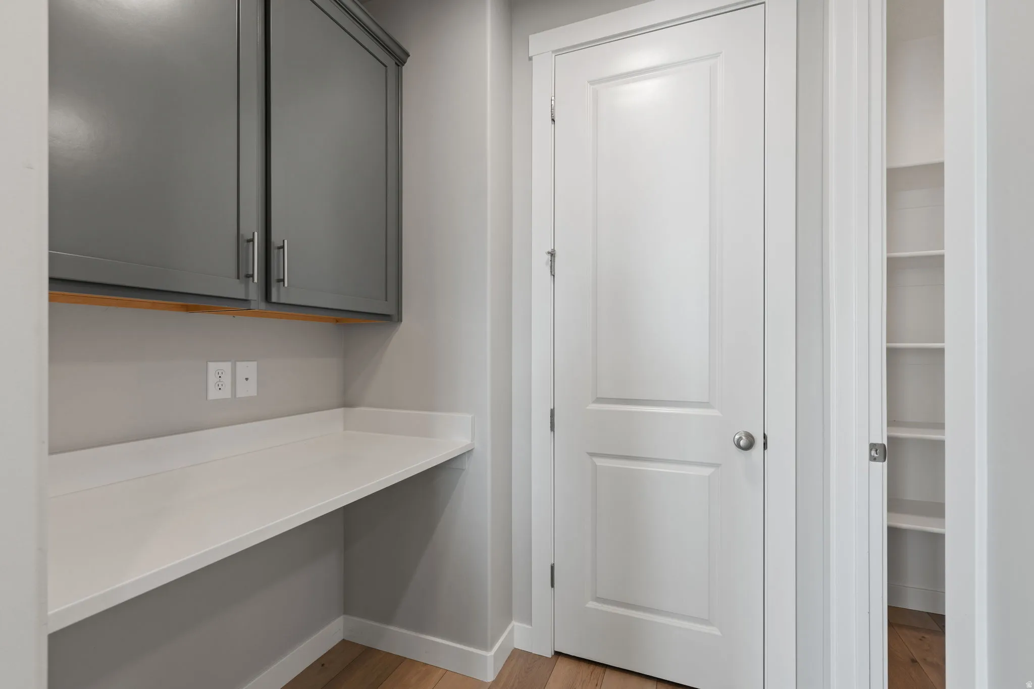 Built-in desk with a white countertop and gray cabinetry