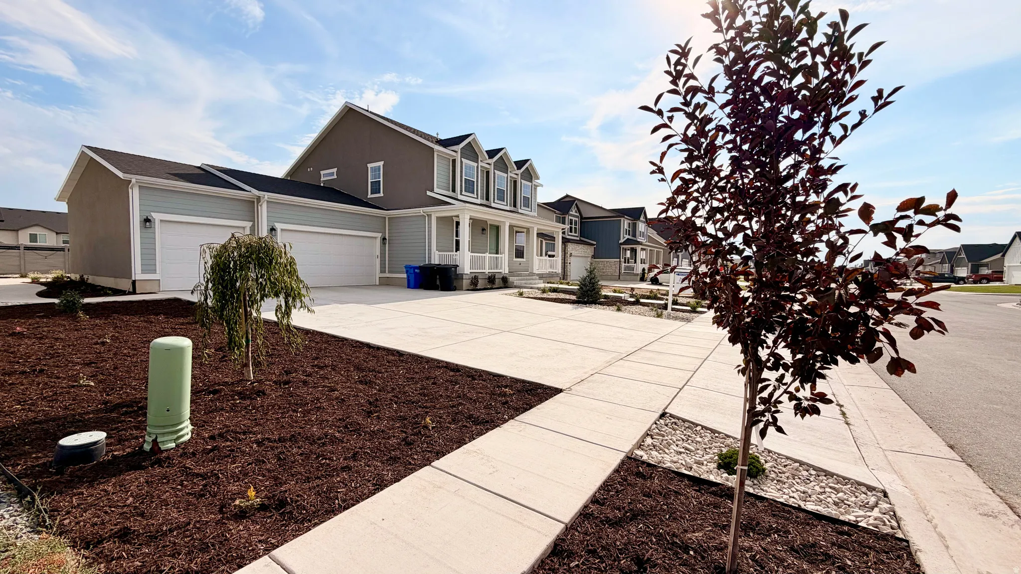 Two-story home with a two-car garage, concrete driveway, and front porch with columns