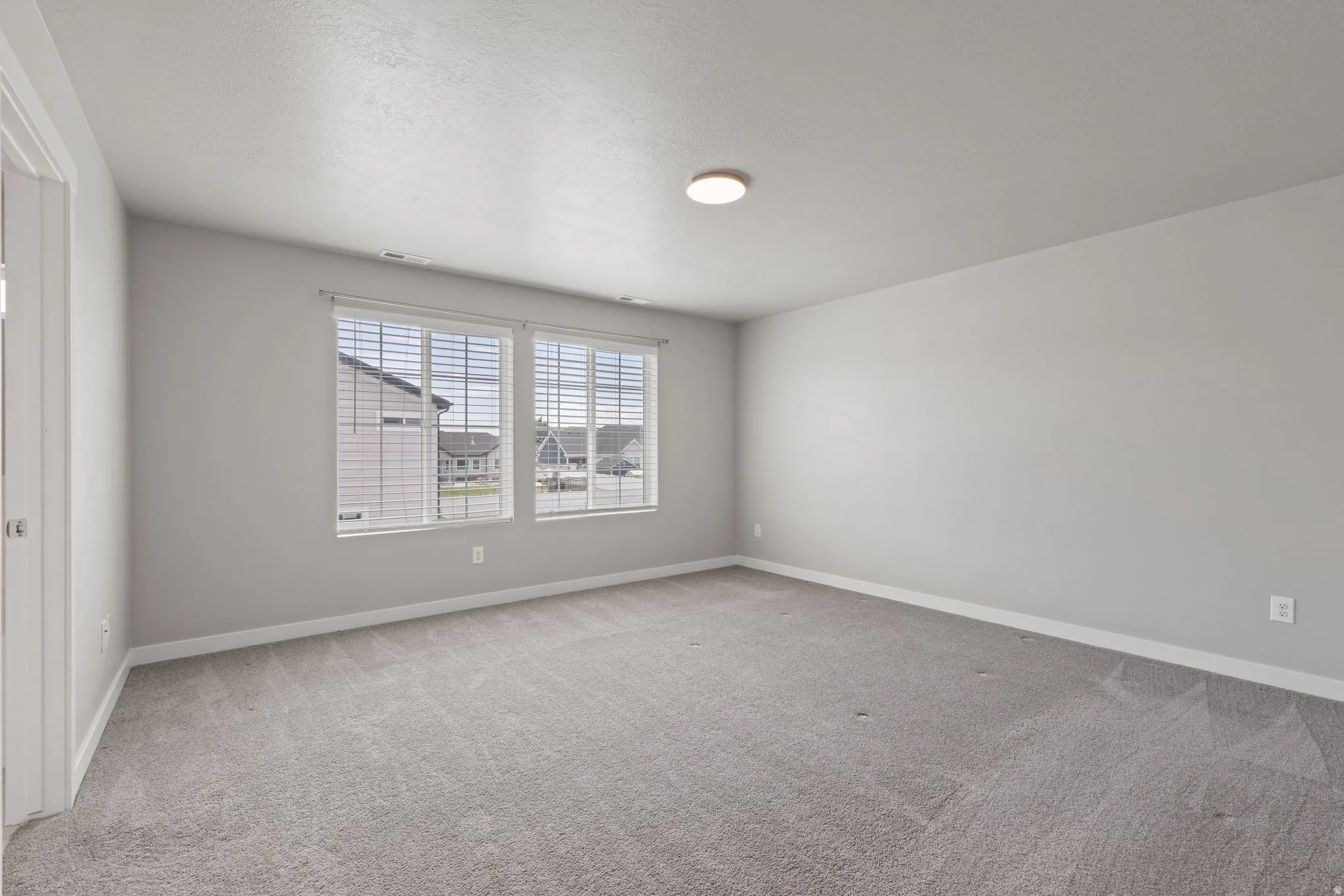 Spacious room featuring gray carpet flooring, light gray wall paint, and white trim