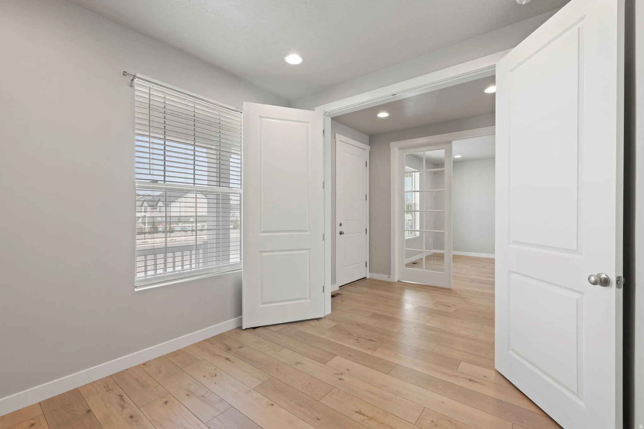 Room featuring wood-finish flooring, recessed lighting, and a window with blinds