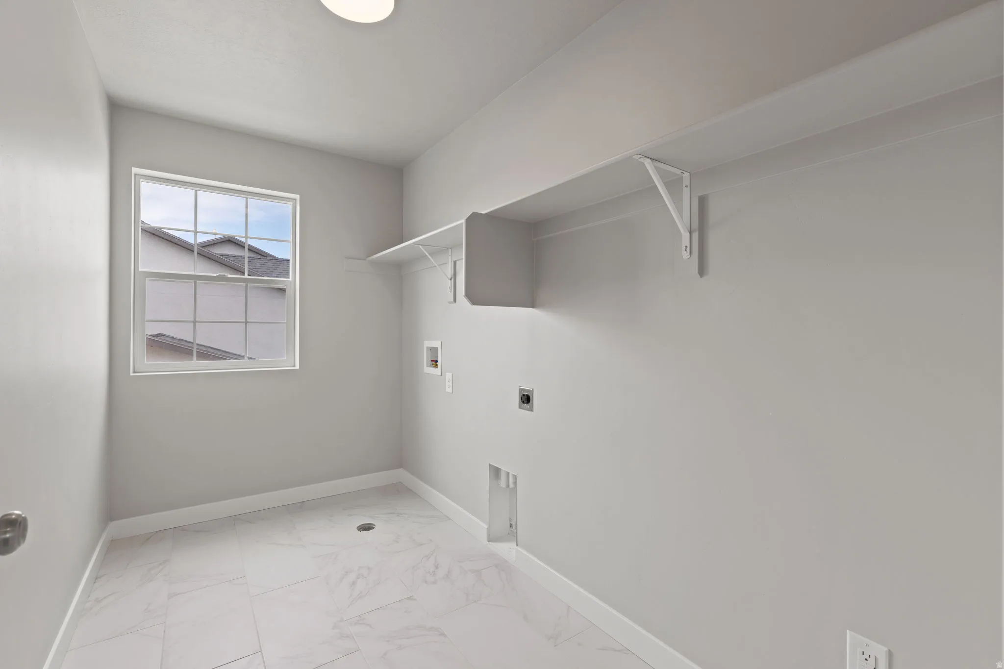 Utility room featuring a window, overhead shelving, and white tile flooring