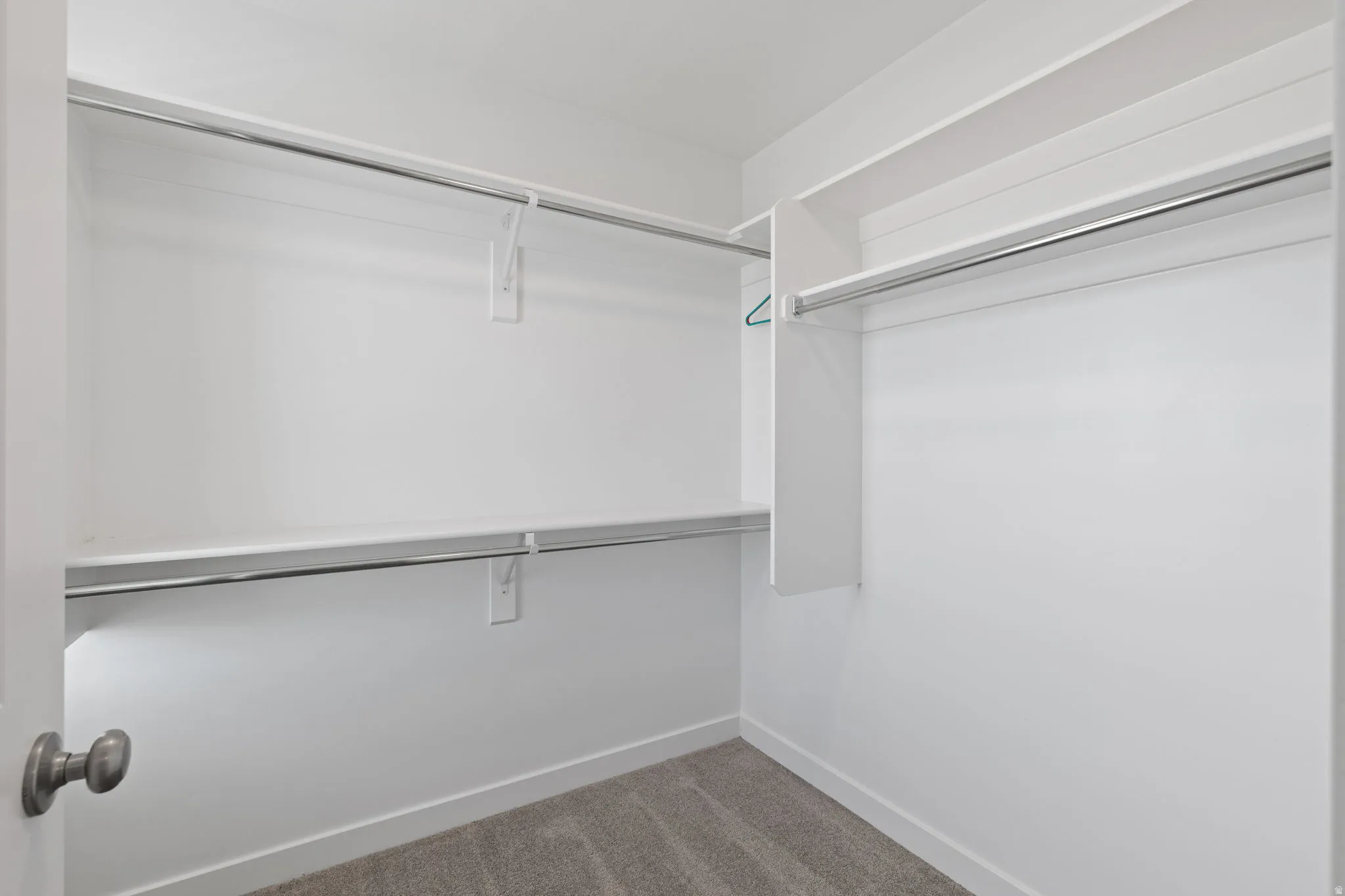 Spacious walk-in closet featuring white shelving and chrome hanging rods