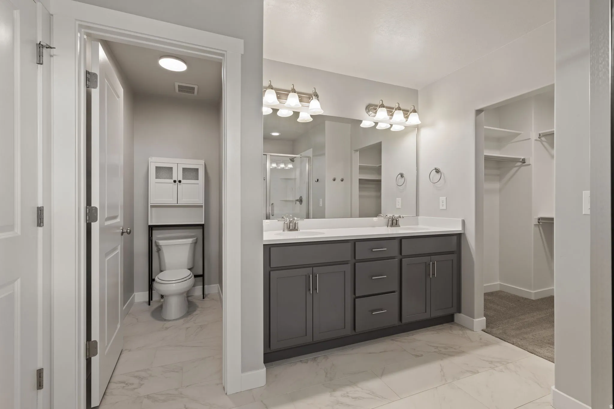 Bathroom featuring a dual vanity with grey cabinetry, white countertops, and brushed nickel fixtures