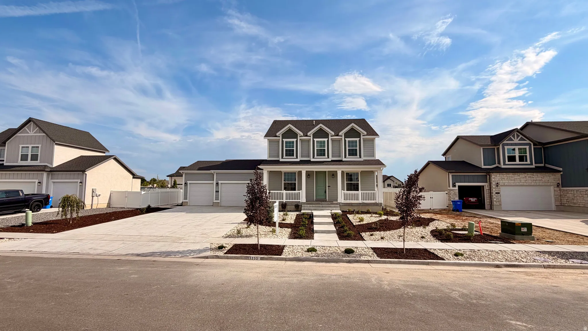 Contemporary two-story residence featuring a covered porch, a three-car garage, and established landscaping